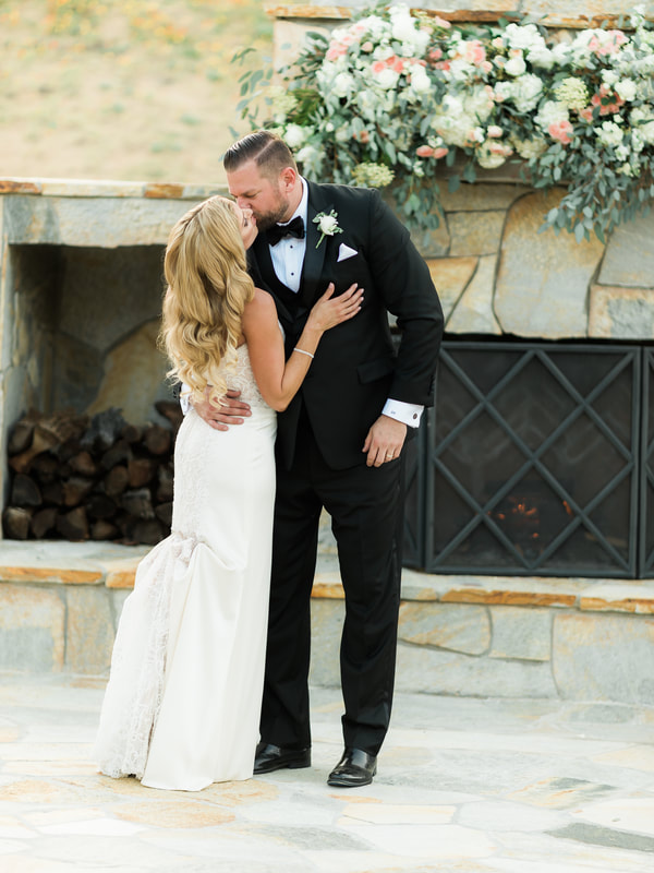 Bride and groom kissing in front of the outdoor fireplace at a murrieta wedding venue