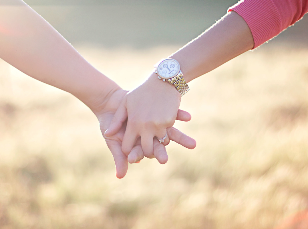 Holding hands in front of a field outdoor.
