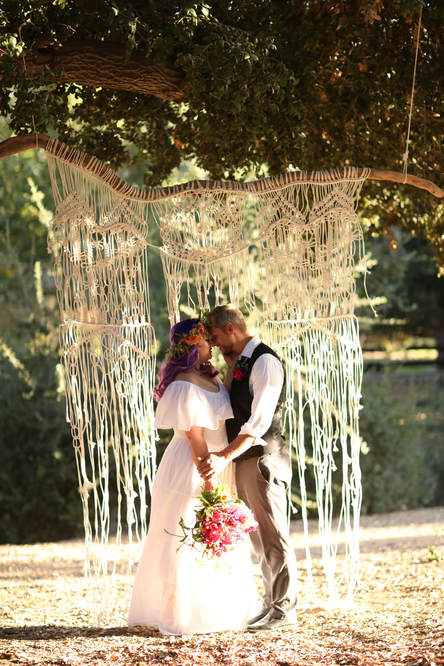 Bride and groom in front of macrame backdrop 