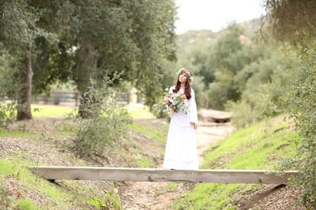Boho bride standing on a wood bridge at this private venue.